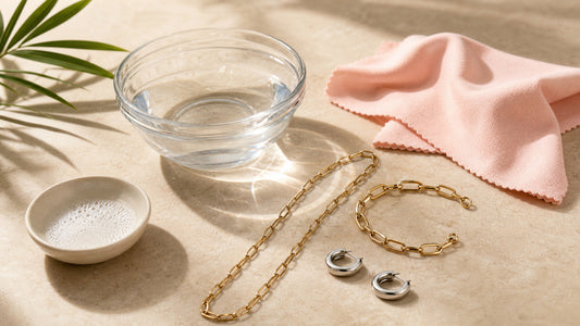 Edelstahlschmuck neben lauwarmem Wasser, milder Seife und weichem rosafarbenem Pflegetuch