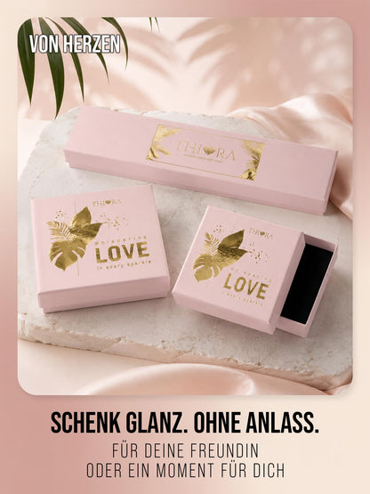 Drei rosa THIORA Schmuckboxen mit Blattmotiv auf einer hellen Steinplatte, eine davon geöffnet.